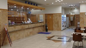 A reception area with a counter labeled "FRONT," a vending machine, and a seating area with tables and chairs. - Toyoko Inn Shin Shirakawa Station (Nishigo)