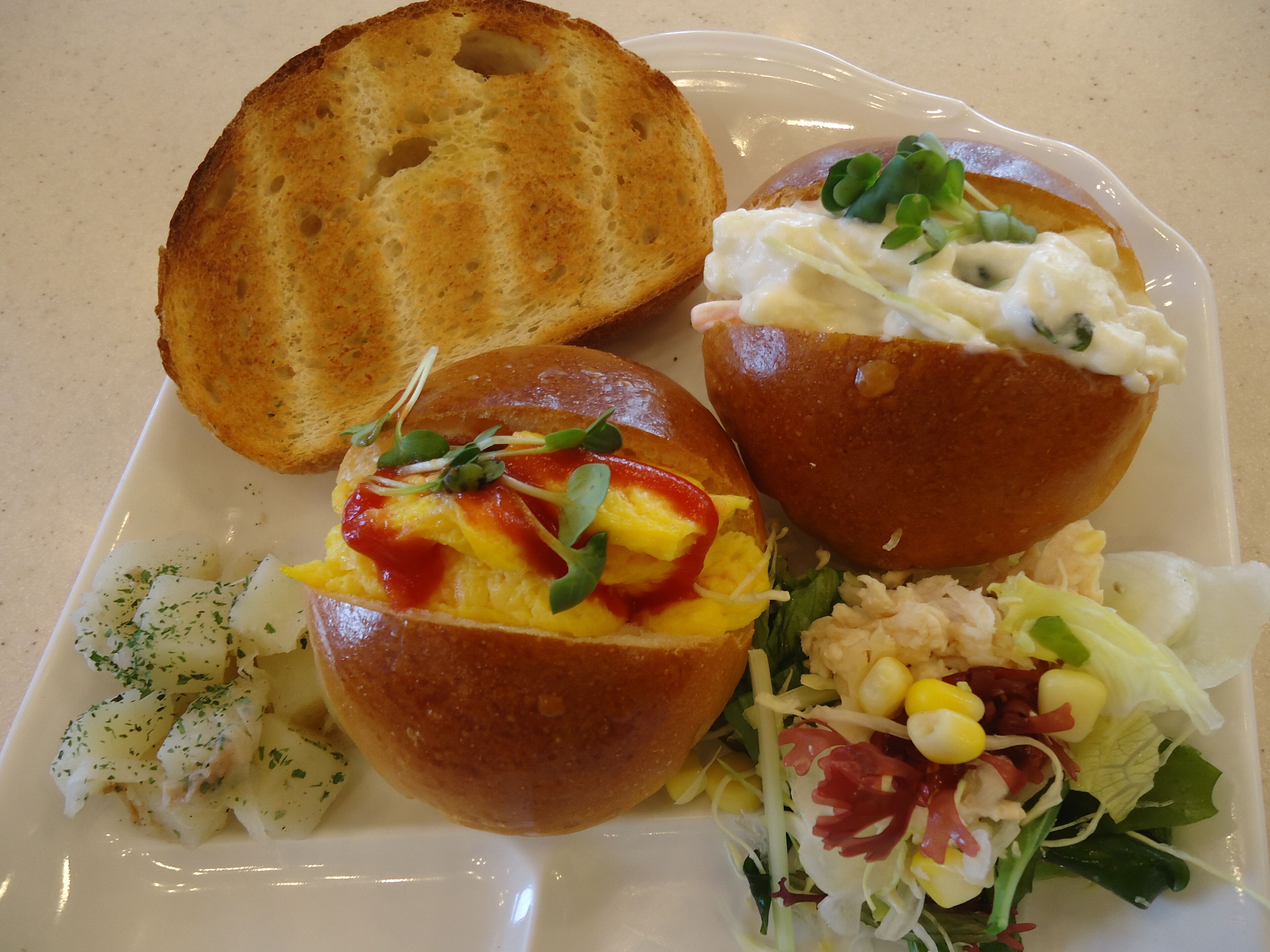 A plate with three open-faced sandwiches, a side salad, and a piece of toasted bread.