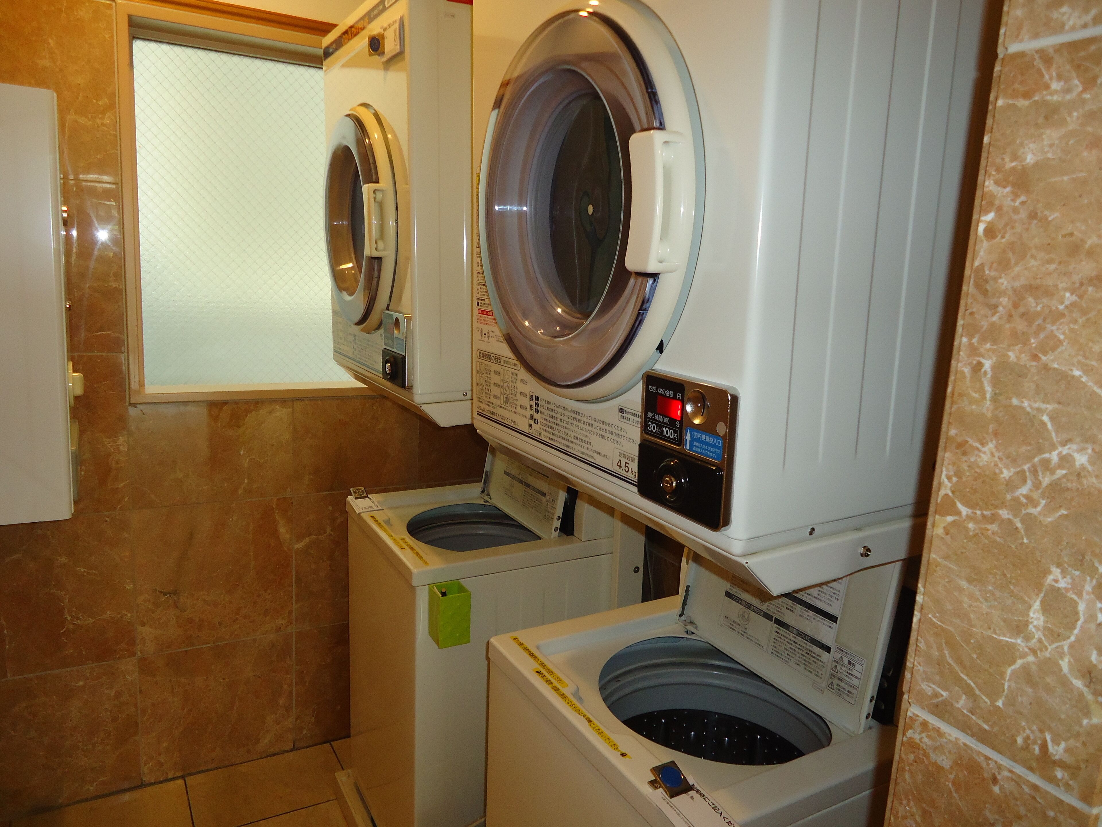 A laundry room with two front-loading washing machines and a dryer.