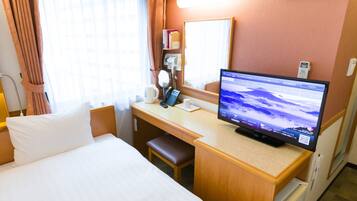 Een hotelkamer met een bed, bureau en een televisie waarop een landschap wordt weergegeven.