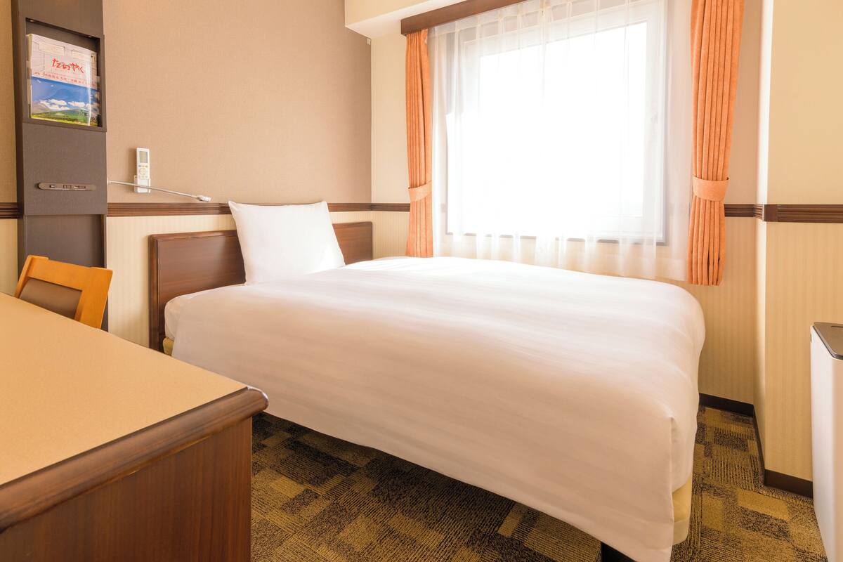 Ein Hotelzimmer mit Bett, Schreibtisch und Stuhl.