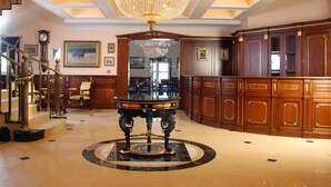 Un hall imponente con una gran lámpara de araña, piso de mármol y un piano de cola.