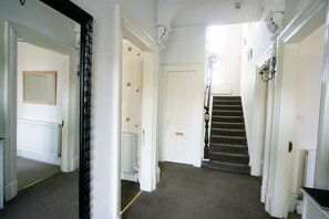 Staircase leads to a carpeted hallway with doors and a radiator.