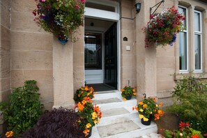 Welcome to a traditional building with a charming entrance, flanked by flower baskets and potted plants.