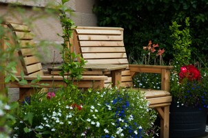 Un conjunto de banco y mesa de madera en un jardín con diversas flores.