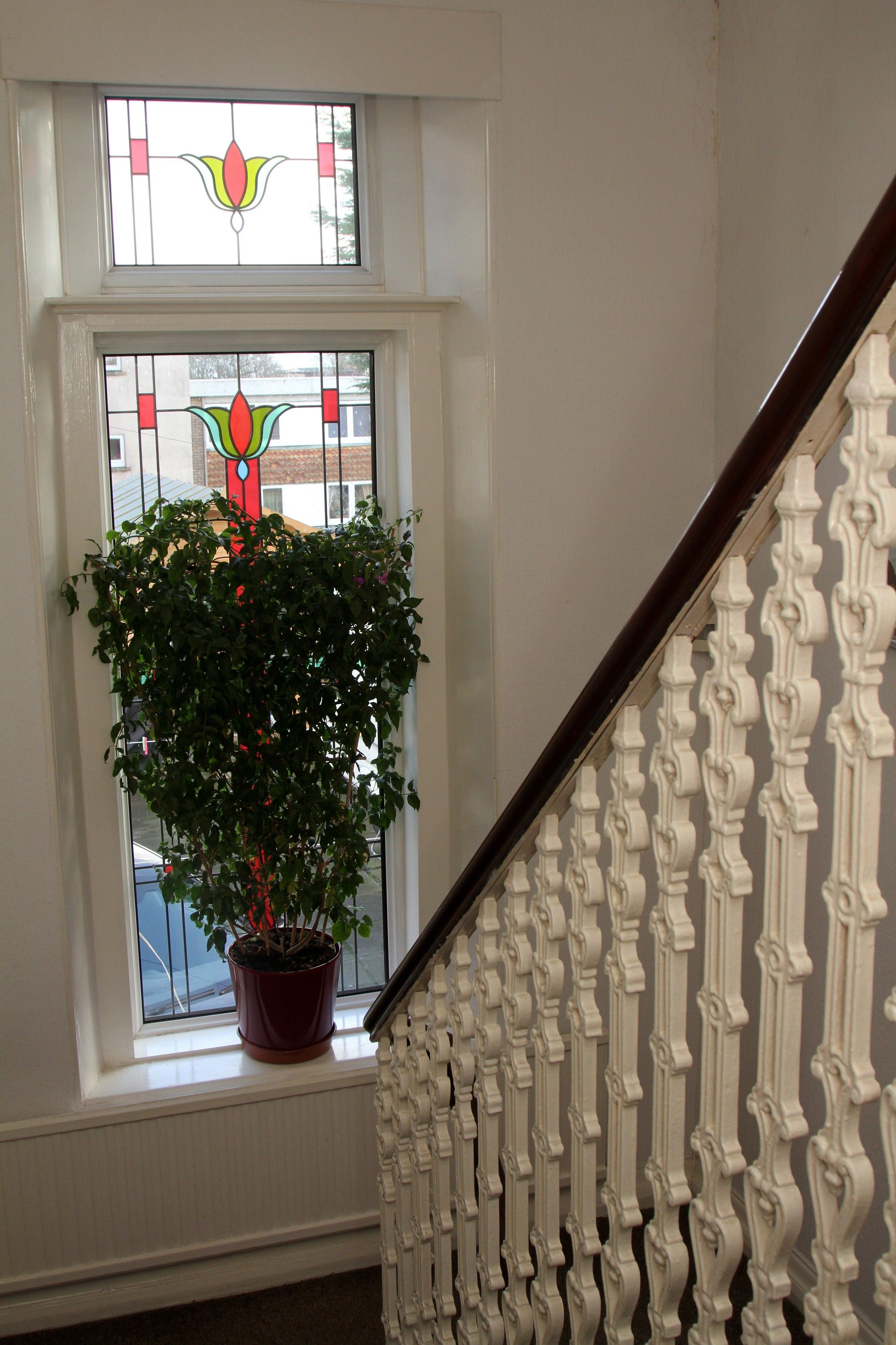 Eine Treppe mit weißem Geländer und einem Blumentopf auf einem Fensterbrett.
