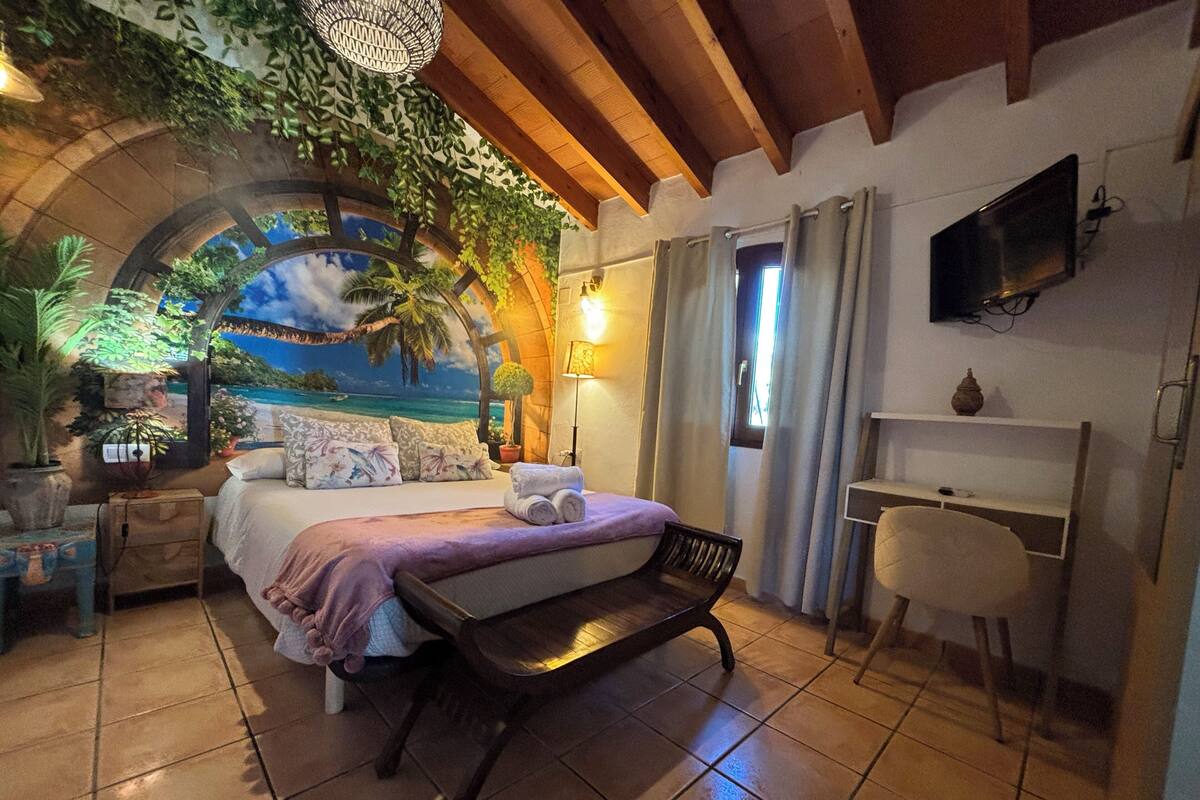A bedroom with a bed, a desk, a chair, and a TV.