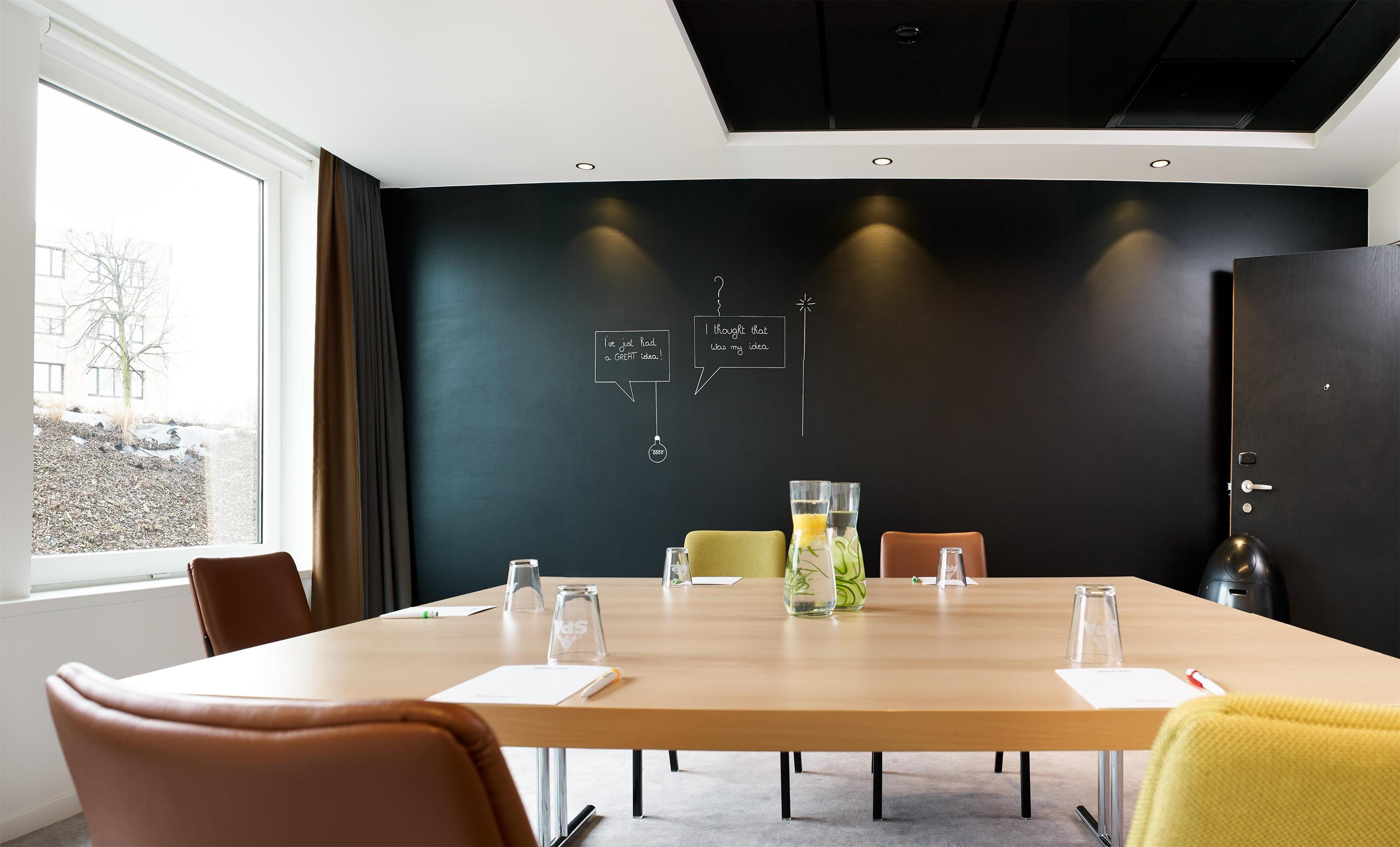 A conference room with a long table, chairs, and a blackboard with handwritten notes.