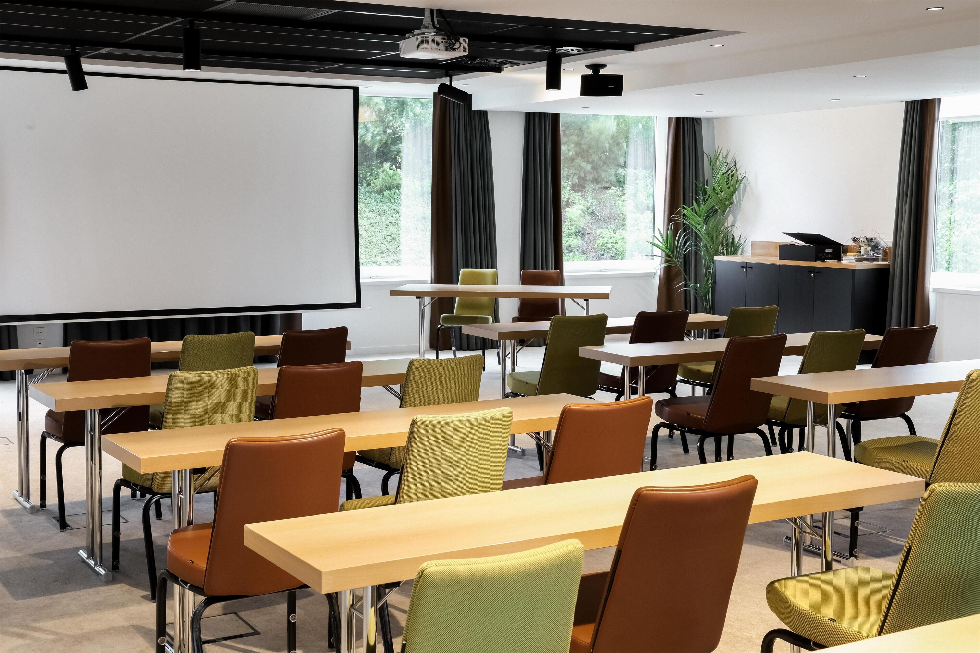 A conference room with tables and chairs, a projector screen, and windows with curtains.
