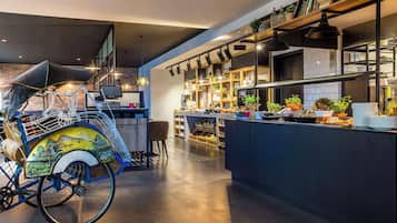 A modern kitchen with a central island, a bicycle with a basket, and a bar area with shelves and plants.