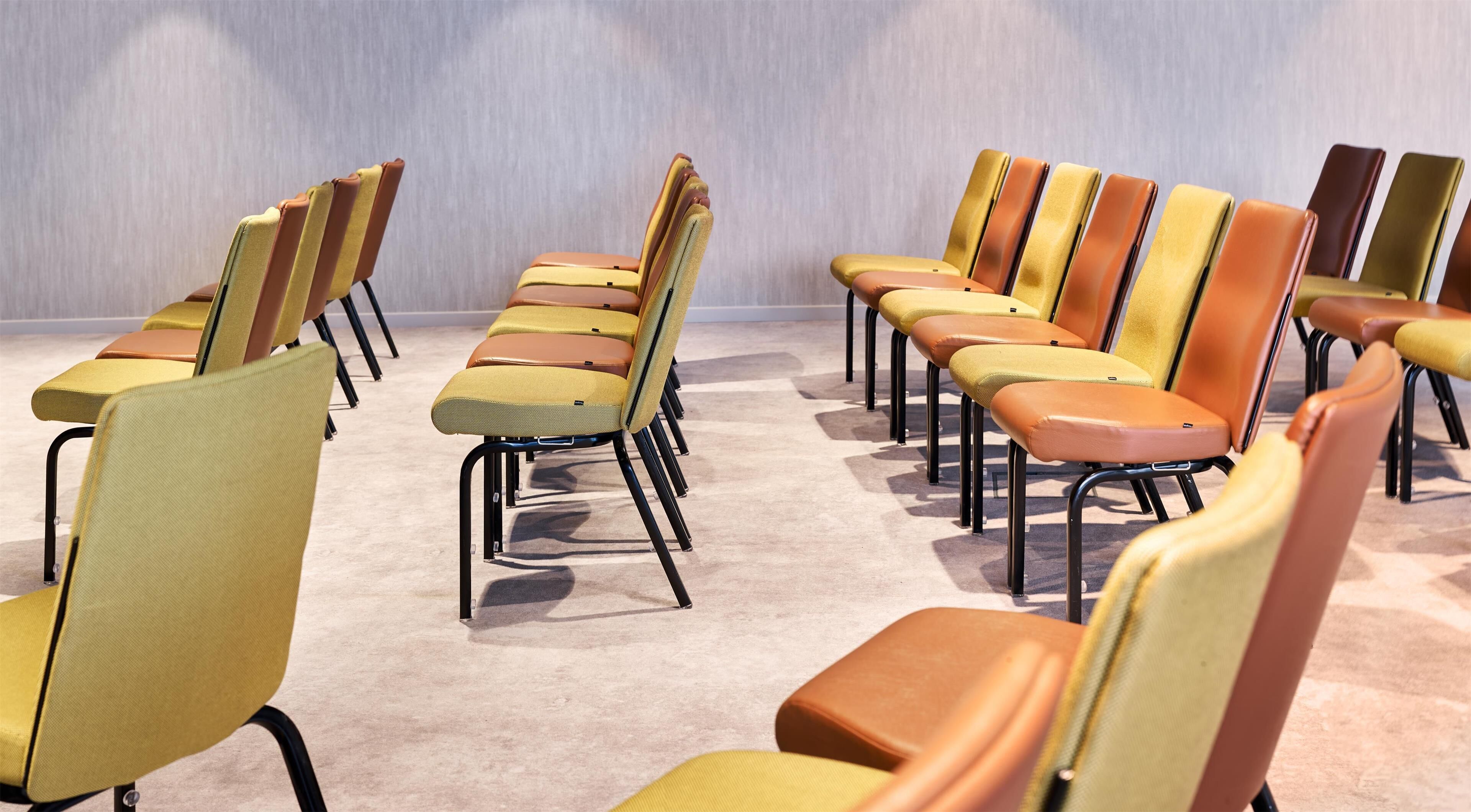 Rows of chairs with a uniform design, arranged in a spacious room with a carpeted floor.