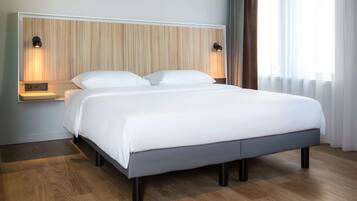 Un dormitorio moderno con cabecera de madera, dos lámparas de noche, una cama grande con ropa blanca y suelo de madera.