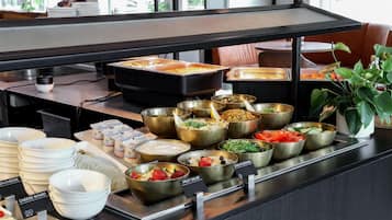 Un buffet proposant une variété de plats et de récipients, notamment un plateau de fromages et une salade de fruits.