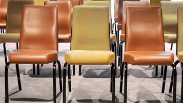 Rows of chairs with black metal legs and cushioned seats in various colors.