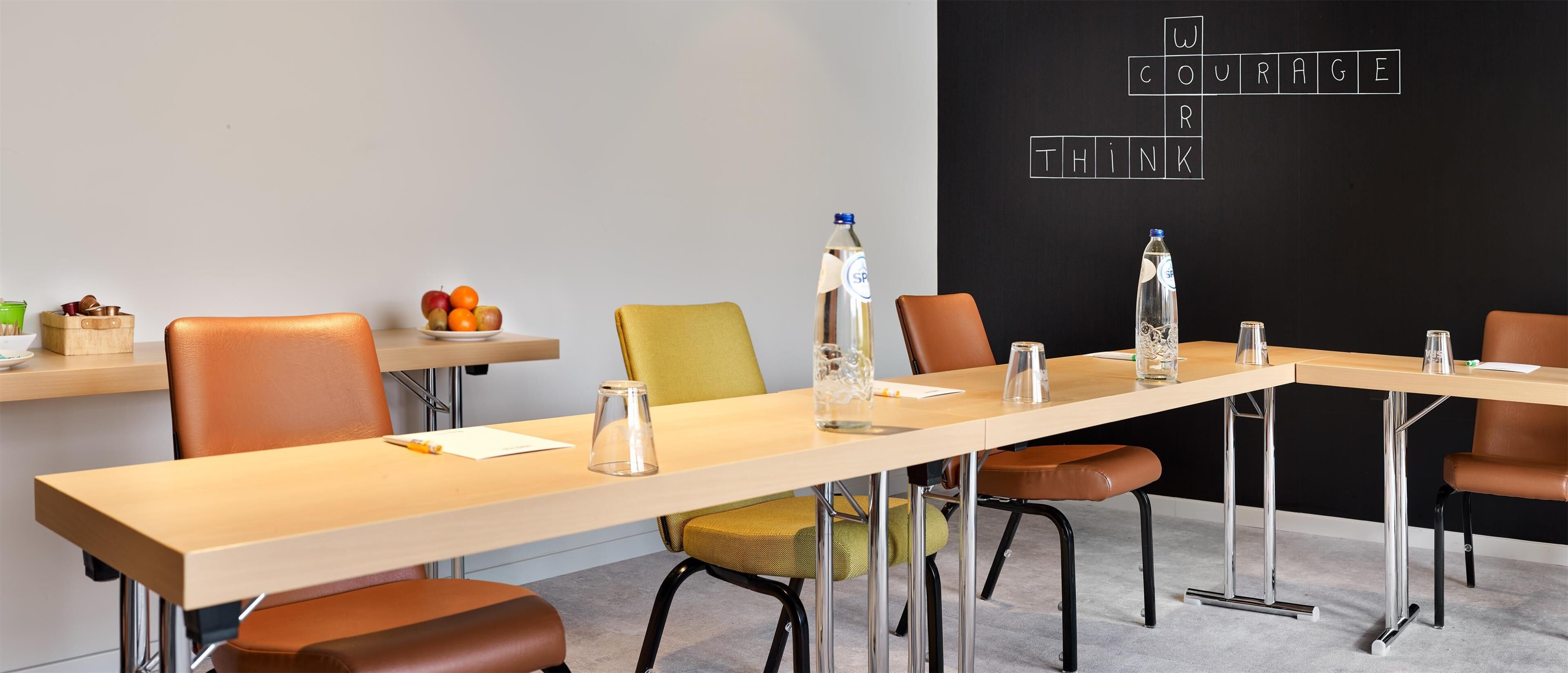 A conference room with a long table, chairs, and a blackboard with a crossword puzzle.