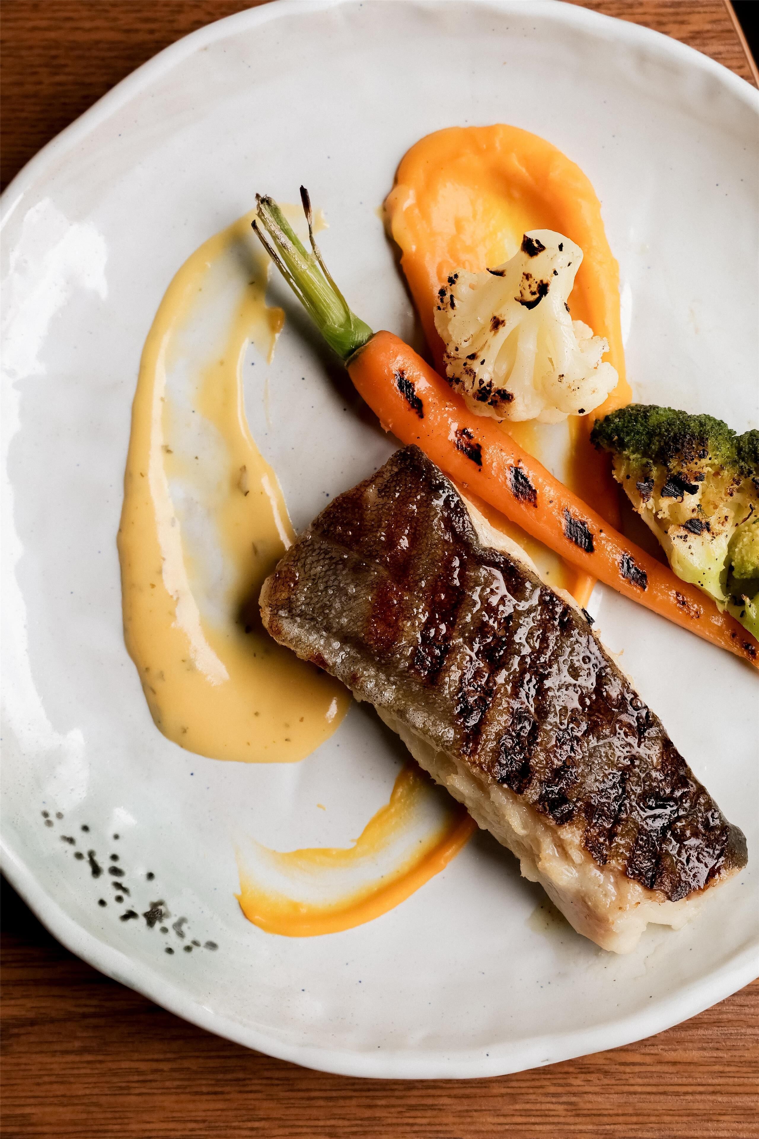 A plate with a steak, grilled vegetables, and a sauce.