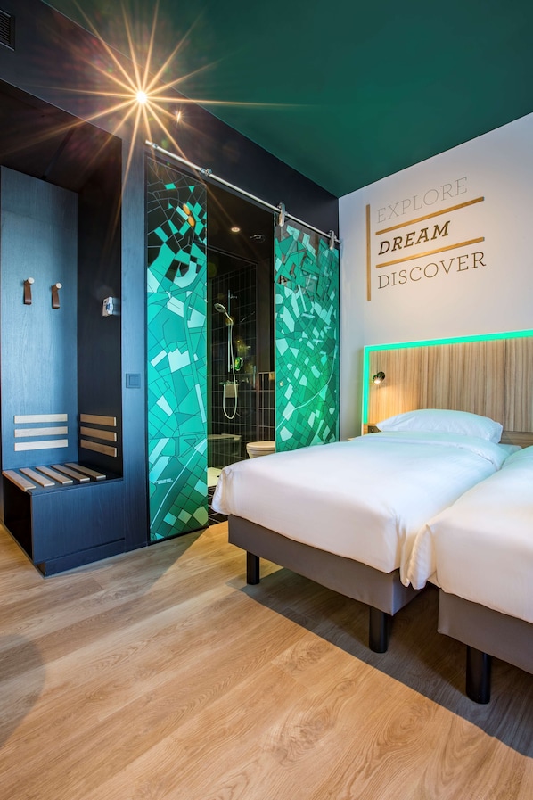 Una habitación de hotel moderna con cama, un banco y zona de ducha.