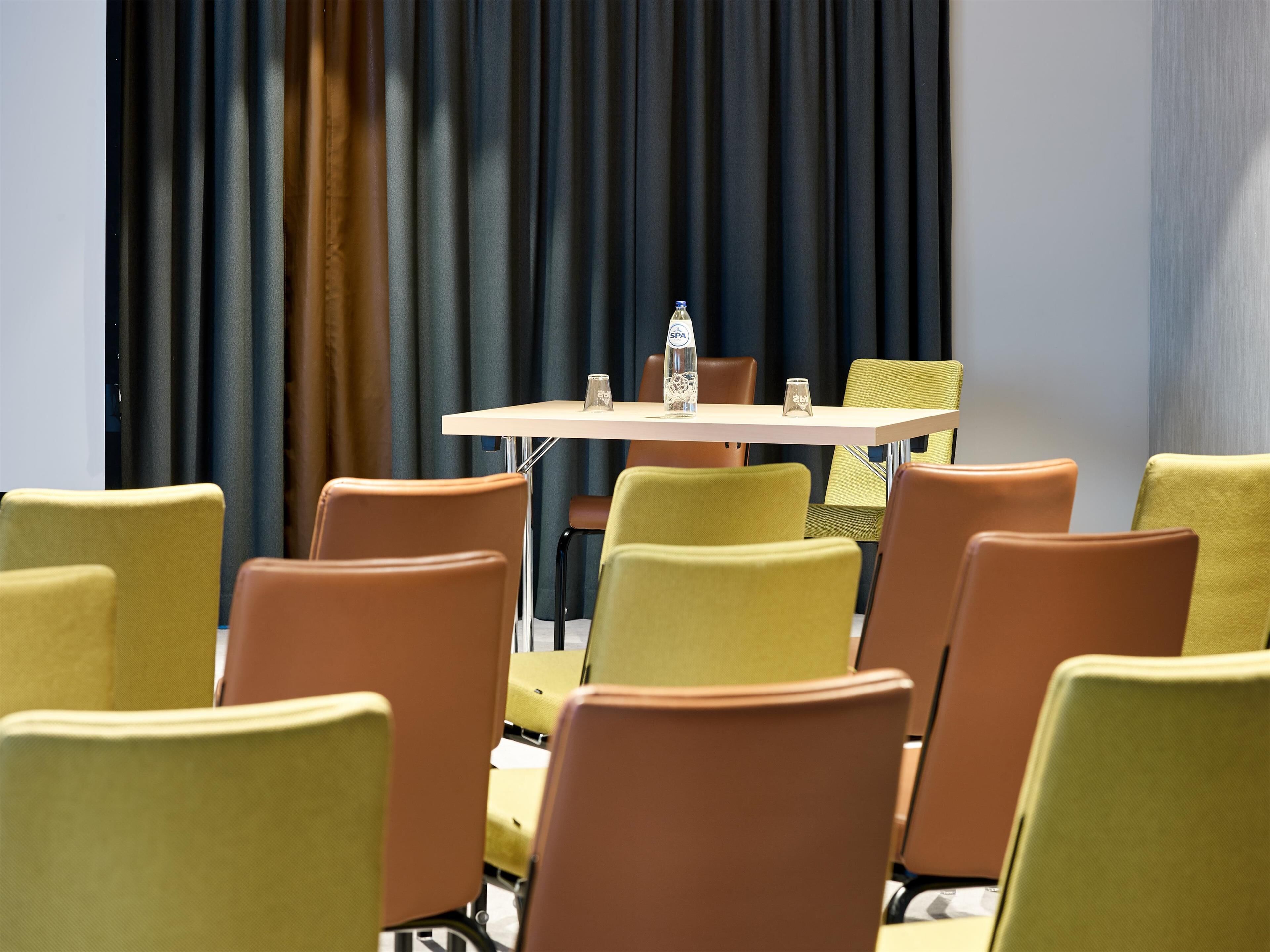 A conference room with a table and chairs, a water bottle, and a glass on the table.