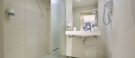A modern bathroom with a glass-enclosed shower, a white sink with a mirror above it, and a toilet.