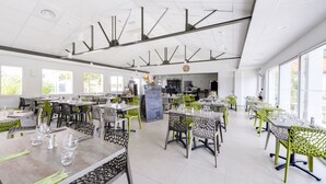 Een ruim restaurant met hoge plafonds, moderne verlichting en een helder interieur.