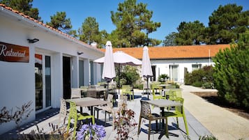 A restaurant with outdoor seating, white walls, and a tiled roof.