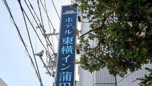 A hotel sign with Japanese characters, surrounded by power lines and a tree.