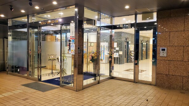 L’entrée d’un hôtel avec des portes vitrées, un sol carrelé et un plafond doté d’un éclairage encastré.