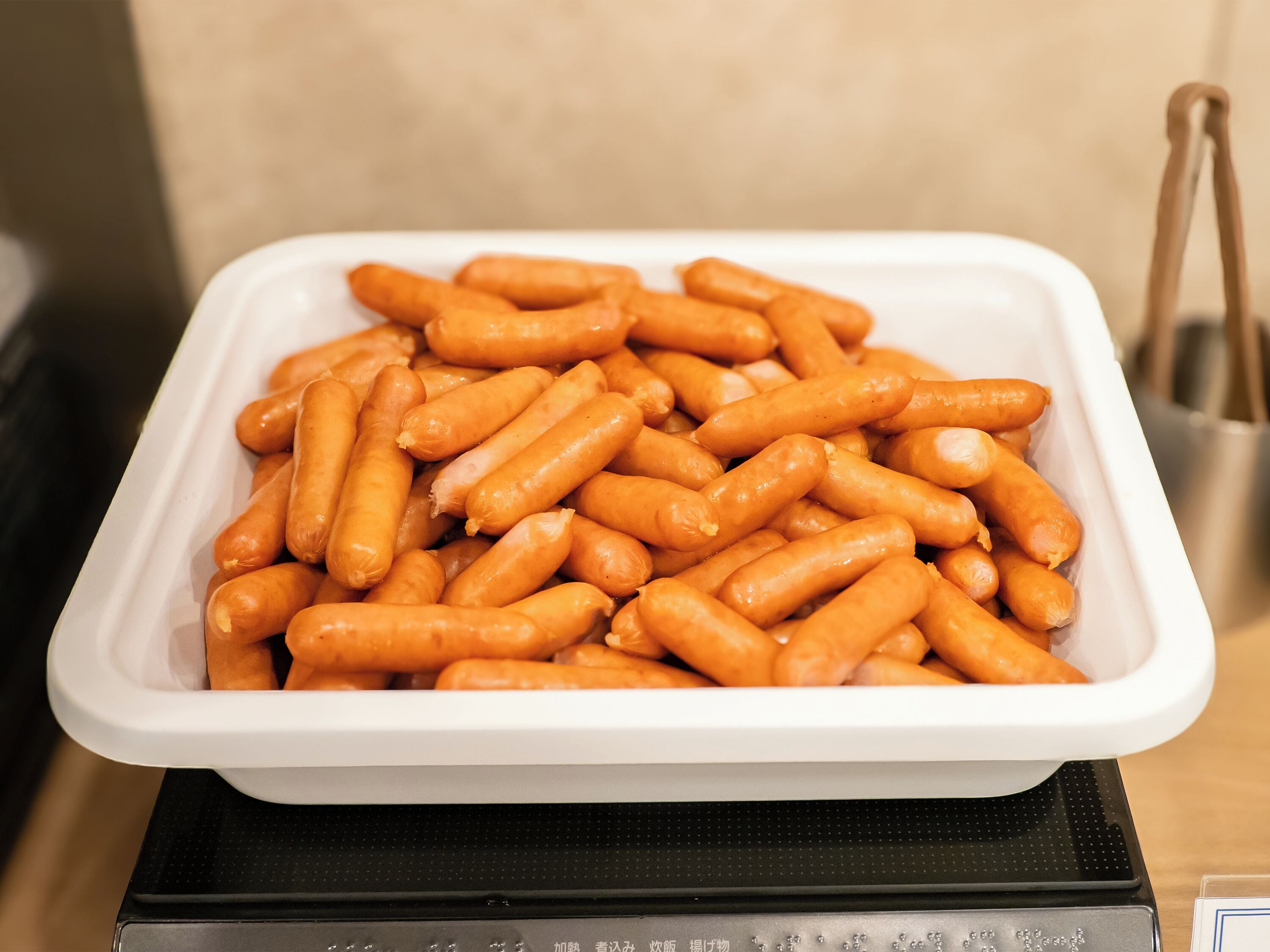 Un plateau blanc rempli de petites saucisses oranges, posé sur une surface noire.