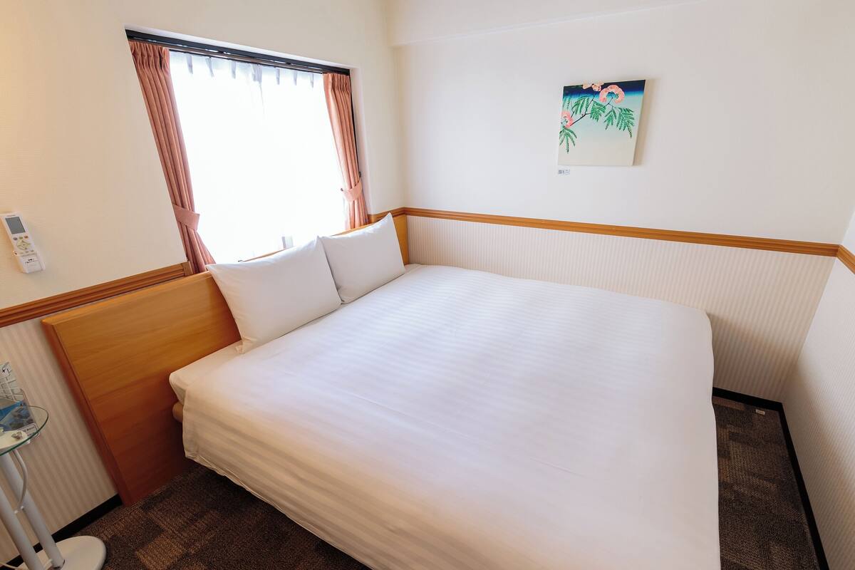 A neatly made bed with white linens in a hotel room.