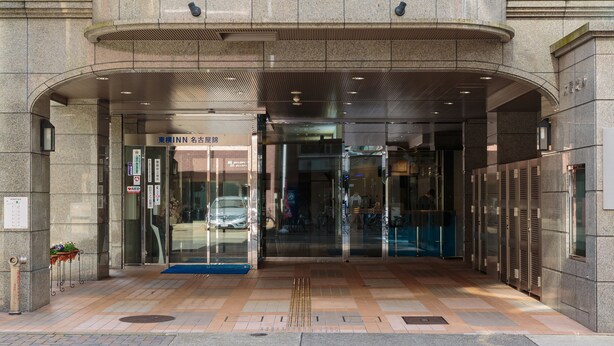 A hotel entrance with a modern design, featuring a large stone facade, glass doors, and a ramp for accessibility.