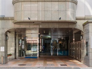 A hotel entrance with a modern design, featuring a large stone facade, glass doors, and a ramp for accessibility. - Toyoko Inn Nagoya Nishiki (Nagoya)