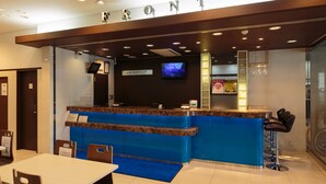 A hotel reception area with a marble counter, a television mounted on the wall, and a sign above the counter reading "FRONT".