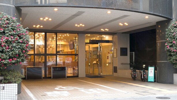 L’entrée d’un hôtel avec une façade en verre, une rampe d’accès pour les personnes à mobilité réduite et un espace de stationnement pour vélos.