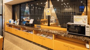Un comptoir d’accueil d’hôtel, un four à micro-ondes Toshiba et une fenêtre donnant sur le paysage urbain.