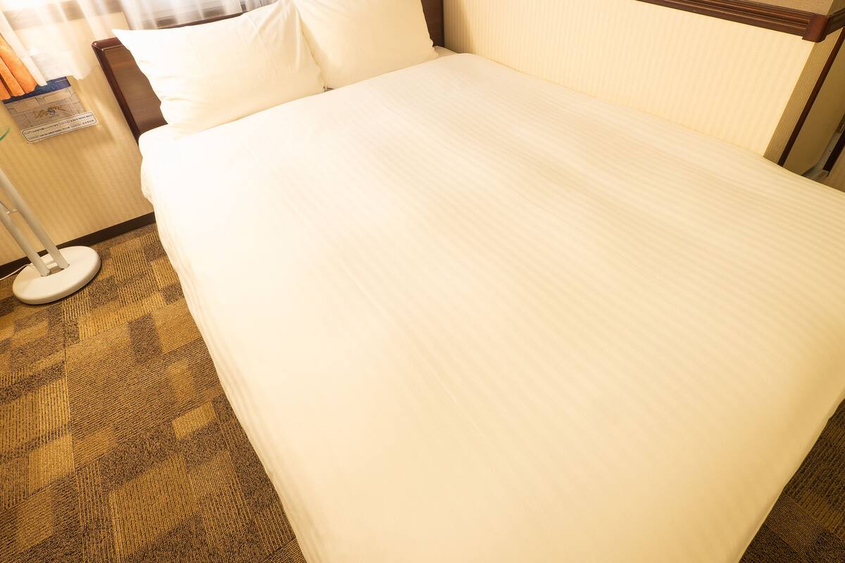 Ein ordentlich bezogenes Bett mit weißen Leinen in einem Hotelzimmer.