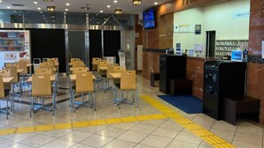 A hotel lobby with a reception desk, seating area, vending machine, and a television screen. - Toyoko Inn Chiba Ekimae (Chiba)