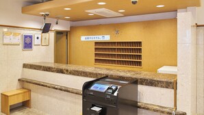 A reception area with a marble counter, a digital check-in kiosk, a small wooden bench, and a wall-mounted clock. - Toyoko Inn Nagoya Station Sakuradori Honkan (Nagoya)