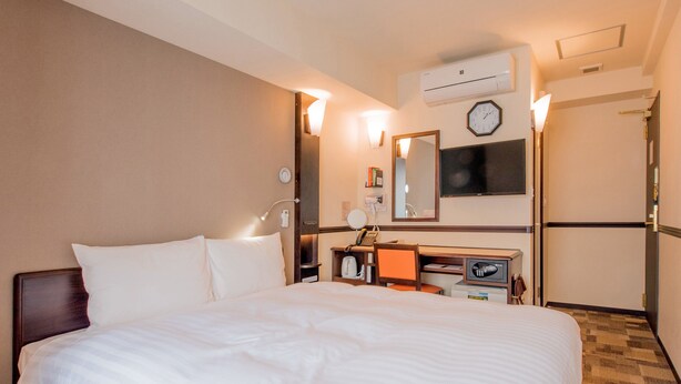 A hotel room with a large bed, a desk with a computer, a mirror, a clock, and an air conditioning unit. - Toyoko Inn Sendai Higashi 2 (Sendai)