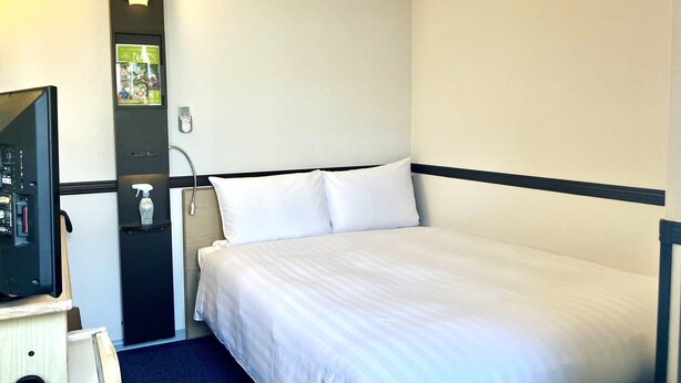 A hotel room with a bed, a desk with a computer, a telephone, and a wall-mounted light fixture. - Toyoko Inn Tokyo Otsuka-eki Kita-guchi No.1 (Tokyo)