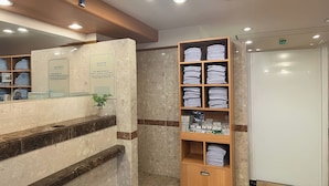 A hotel reception area with a marble counter, a wooden shelf with folded towels, and a reception desk. - Toyoko Inn Tokyo Otsuka-eki Kita-guchi No.1 (Tokyo)