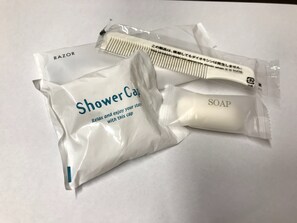 Un paquete con la etiqueta 'Shower Cap', un peine y una barra de jabón.