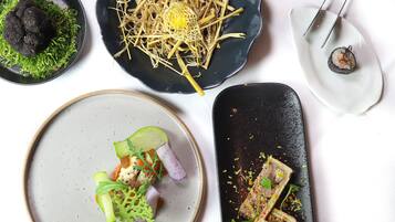 A variety of dishes on different plates, including sushi, a salad, and a dish with meat and herbs.