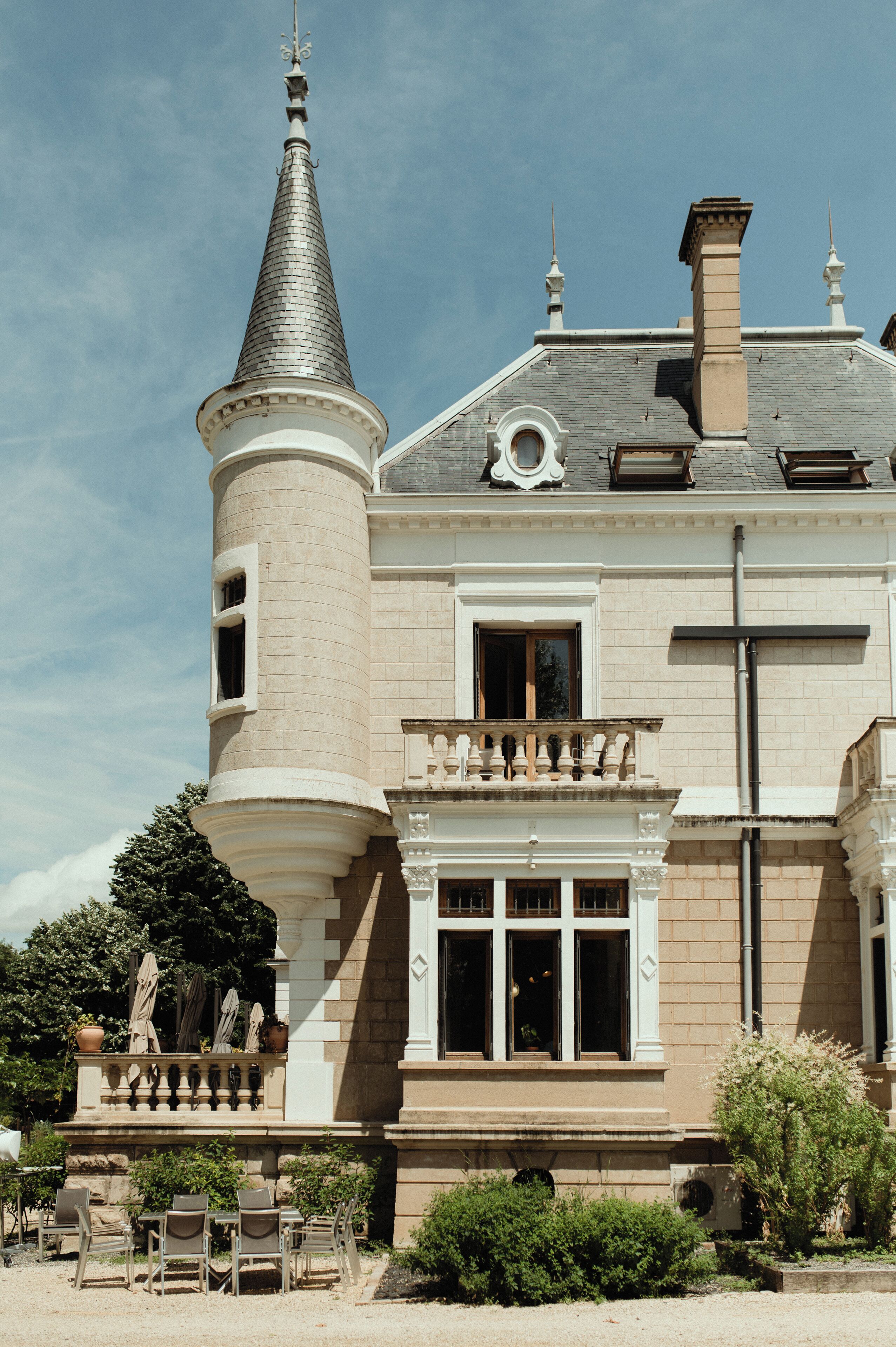 A large, historic building with a prominent turret and a balcony with ornate railings.