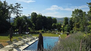 Ein Poolbereich mit Liegestühlen und Sonnenschirmen, umgeben von Grünpflanzen und Lavendel.
