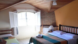 Une chambre à coucher comprenant un lit, une table de chevet, une lampe, une fenêtre avec des volets et un ventilateur de plafond.