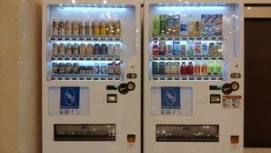 Dos máquinas expendedoras con una variedad de bebidas y aperitivos, cada una con el logotipo y la página web toyoko-inn.com.