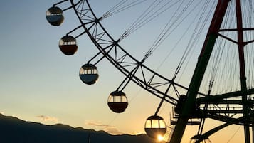 A cable car system with multiple gondolas, a large metal structure, and a mountainous backdrop during sunset.