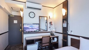Habitación de hotel con cama, escritorio, silla y televisor que muestra un paisaje montañoso.