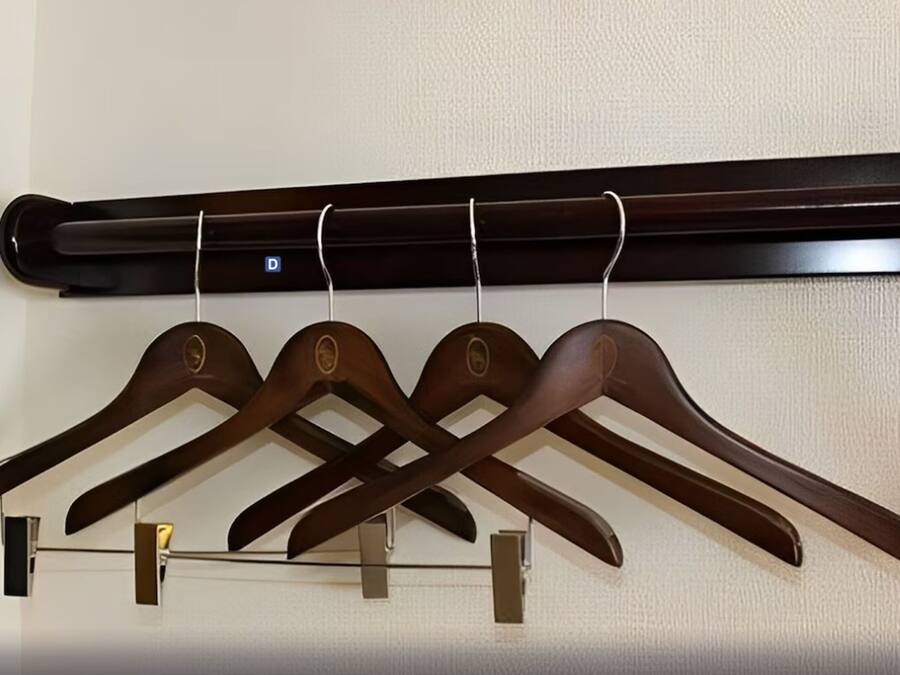 A wall-mounted wooden coat rack with four hangers.