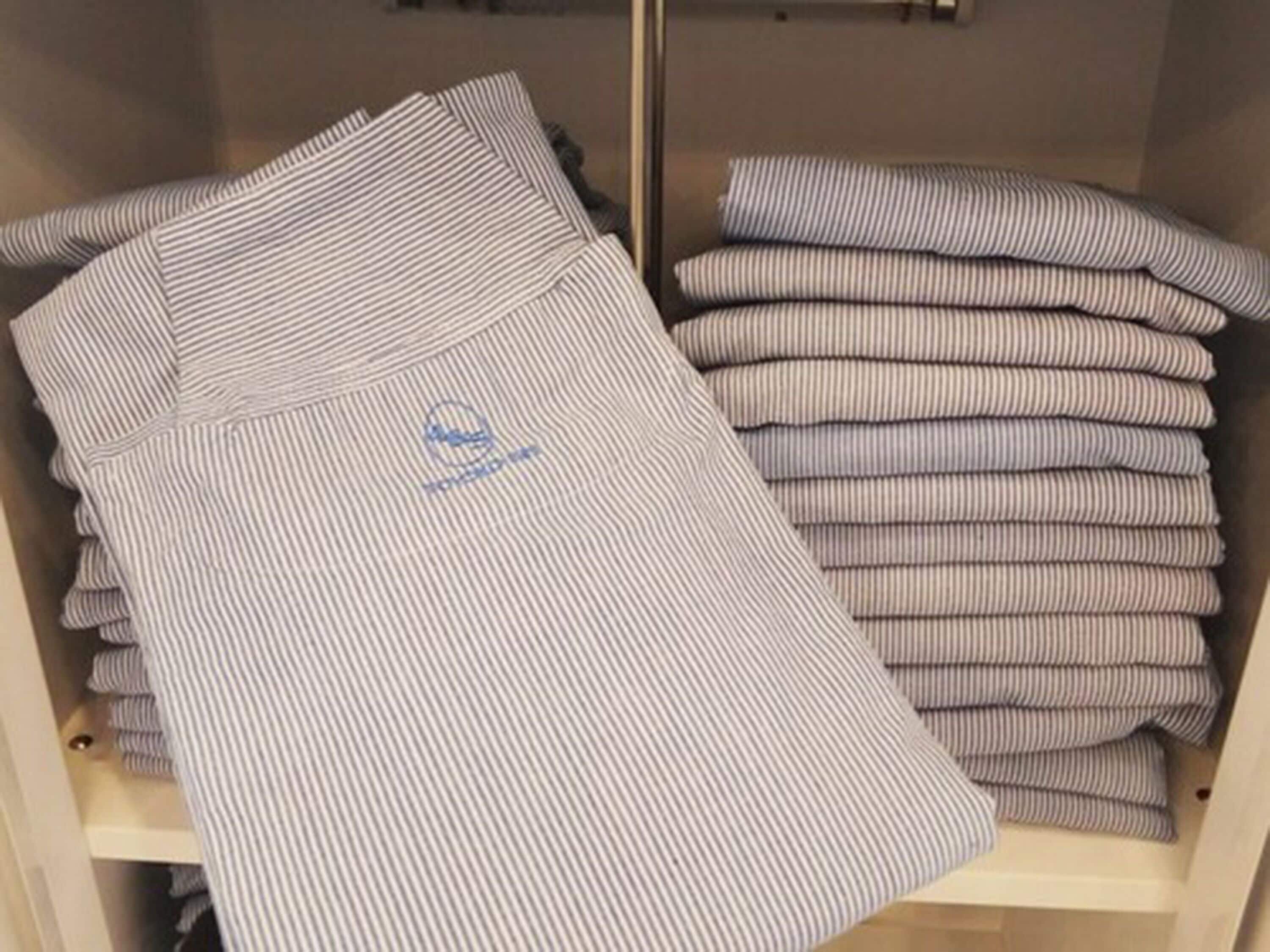 Neatly folded striped shirts in a storage closet.